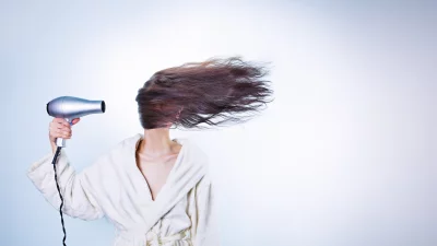 Faceless Woman in White Robe Dynamically Drying Long Hair with Hairdryer image