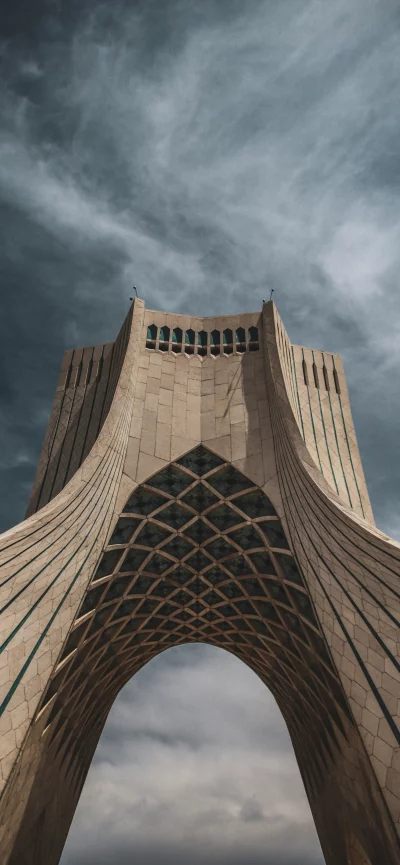 Azadi Tower architecture against dramatic cloudy sky in Tehran, Iran