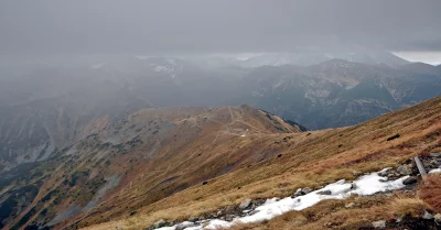 Rugged Mountain Landscape with Winding Trails and Patches of Snow Under Cloudy Skies image
