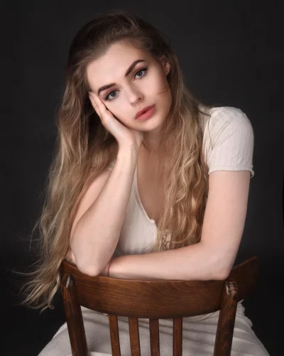 Contemplative Blonde Woman on Wooden Chair with Pensive Gaze image