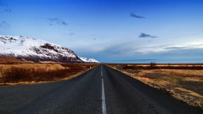 Remote Asphalt Road Through Vast Icelandic Landscape with Snow-Capped Mountains image