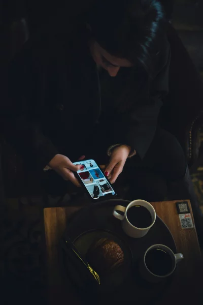 Woman browsing fashion on smartphone with coffee and pastry