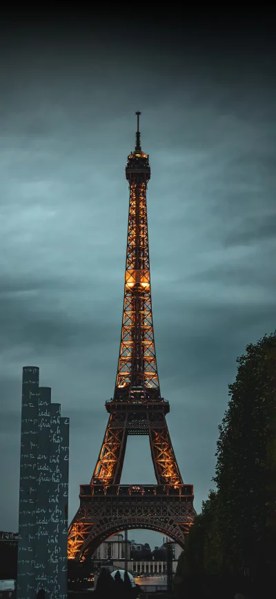 Iconic Eiffel Tower Illuminated Against a Moody Evening Sky in Paris