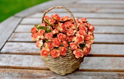 Wicker Basket Filled with Orange Pink Artificial Flowers on Rustic Wooden Table image