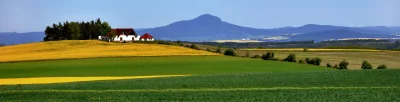 Lush Green and Golden Yellow Fields with Quaint House and Distant Mountains image