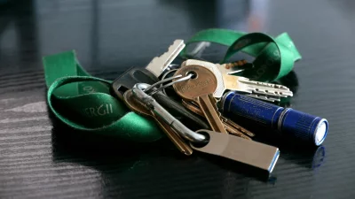Set of House and Car Keys with Blue Flashlight and Green Ribbon on Dark Wood image