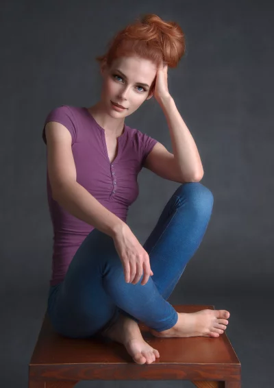 Stunning Redhead Woman Sitting Casually Posing in Studio Looking at Camera image