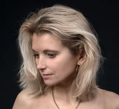 Pensive Blonde Woman with Tousled Hair and Gold Hoops in Studio Portrait image
