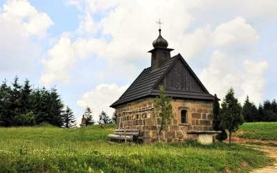 Historic Stone Chapel on Grassy Hillside with Traveler and Pine Forest Landscape image