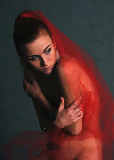 Pensive Young Woman Veiled in Red Sheer Fabric with Elegant Jewelry image