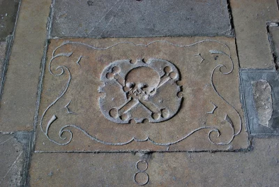 Ancient Skull and Crossbones Carving on Historic Stone Floor Texture image