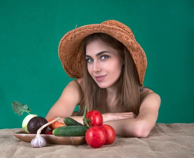 Smiling Young Woman in Straw Hat Posing with Fresh Garden Vegetables image