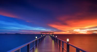 Illuminated Pier at Sunset with Vibrant Ocean Sky Reflection image