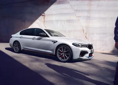 White BMW M5 Performance Sedan with M Stripes against Cracked Wall image