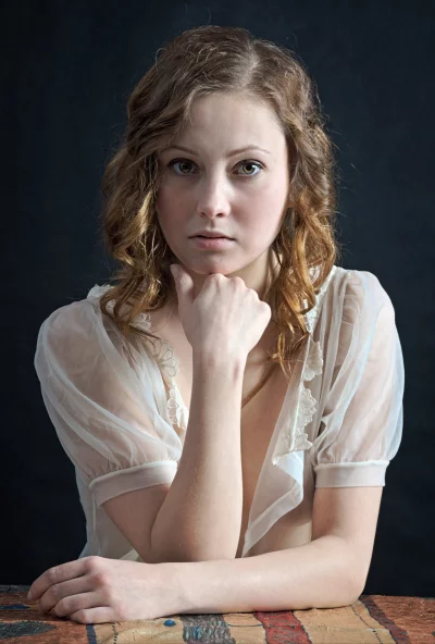 Pensive Young Woman with Reflective Gaze in Elegant Sheer Blouse Portrait image