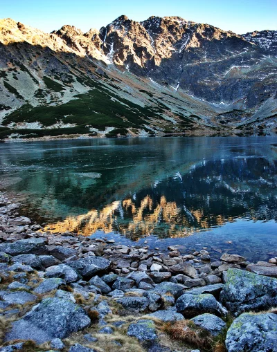 Golden Hour Sunlight on Majestic Mountains Reflected in Partially Frozen Alpine Lake image