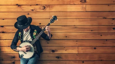 Folk Musician Playing Banjo with Embroidered Shirt and Cowboy Hat Against Rustic Wood image