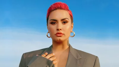 Empowered Individual with Vibrant Pink Hair, Gold Jewelry, and Elegant Blazer Under Blue Sky image