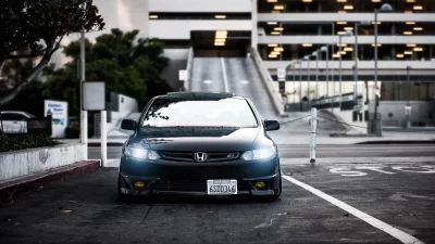 Stylish Black Honda Civic Si Coupe with Bright Headlights in Urban Parking Lot image