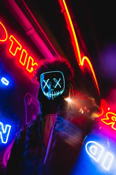 Mysterious Figure in Glowing Neon Mask Amidst Urban Night Lights Wallpaper image