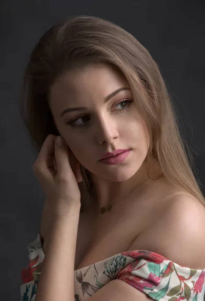 Elegant Young Woman with Pensive Gaze, Floral Off-Shoulder Dress, Gold Necklace image