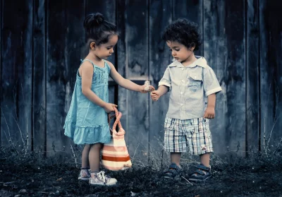 Childhood Innocence: Girl Offers Dandelion Fluff to Boy in Rustic Setting image