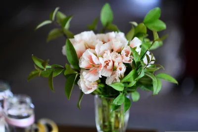 A beautiful bouquet of flowers And flowers are mostly white with a light pink tinge, and they are arranged in a vase with greenery