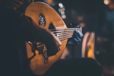 Musician's Hands Skillfully Playing Traditional Oud Instrument in Dimly Lit Setting image
