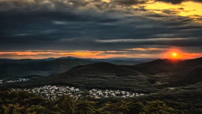 Dramatic Sunset Over Forested Hills and Village with Golden Hour Sky image