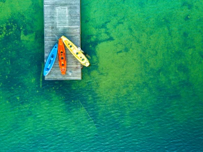 Colorful Kayaks Moored to Wooden Pier on Vibrant Green Lake Water image