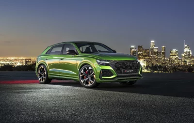 Dynamic Green Audi RS Q8 Luxury Performance SUV at Night Against Illuminated City Skyline image