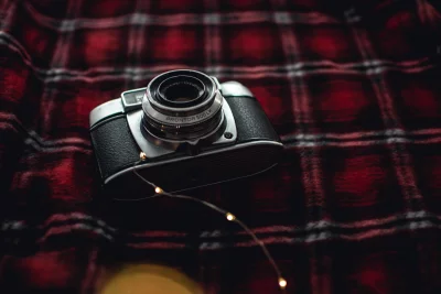 a close-up of a vintage camera lying on a red and black checkered blanket