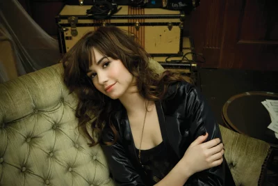 Charming Brunette Woman Relaxing on Tufted Sofa with Subtle Smile and Vintage Props image