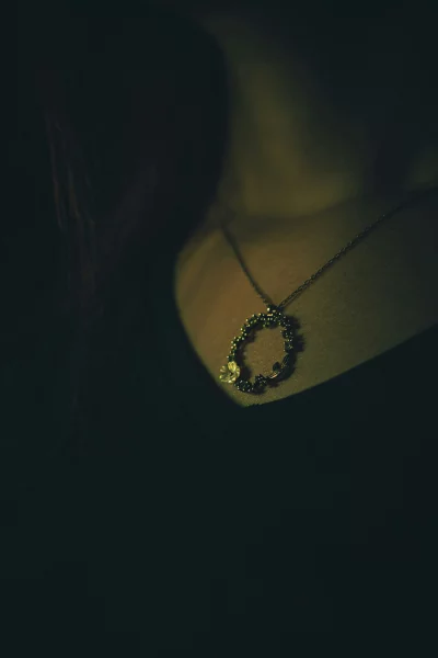Delicate Floral Necklace in Dramatic Low Light on Woman's Collarbone