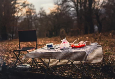 Camp picnic table with food and chair in autumn forest at sunset