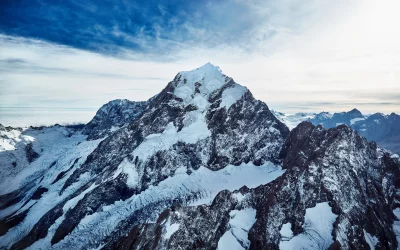 Aerial Perspective of Towering Snow-Covered Mountain, Expansive Glaciers, and Ethereal Clouds image