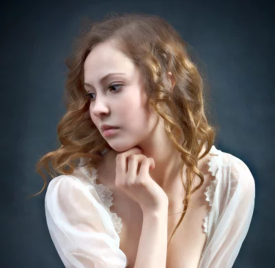 Graceful Young Woman with Thoughtful Expression and Wavy Auburn Hair in Soft Light image