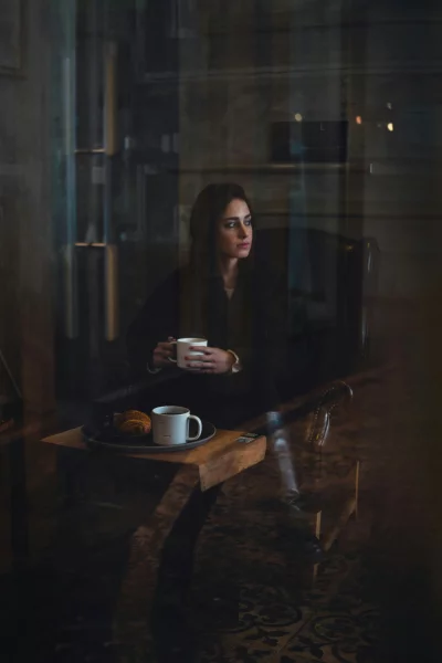 Elegant Woman Enjoying Coffee and Croissant in Reflective Cafe Window