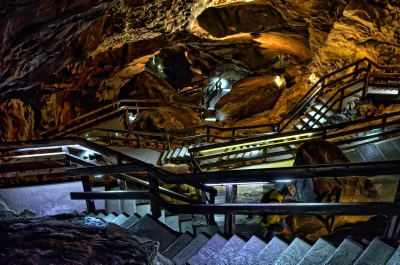 Illuminated Underground Cave with Tourist on Winding Stairs image