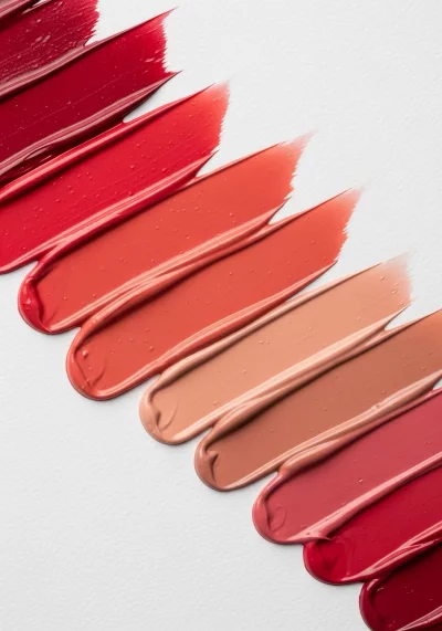 Vibrant Red to Nude Lipstick Swatches on White Textured Background