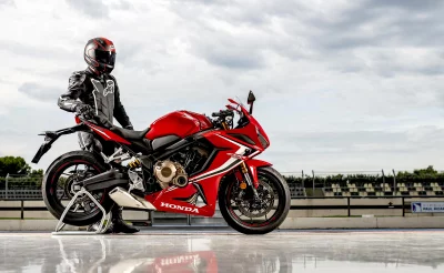 Professional Motorcyclist in Full Racing Gear with a Powerful Red Honda CBR 650R Sportbike on a Circuit image