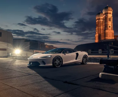Sleek White Sports Car Parked at Dusk with Historic Building Cinematic Wallpaper image