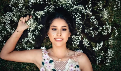 Smiling Young Woman Reclining on Grass with Delicate White Flowers image