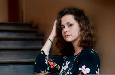 Pensive Young Woman with Curly Brown Hair and Striking Blue Eyes image