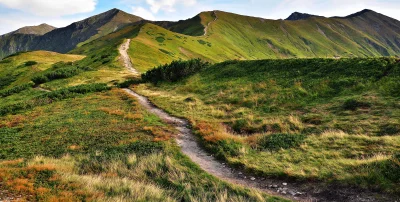 Winding Hiking Path Ascends Majestic Green Mountains Under a Clear Sky image