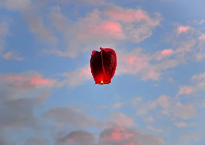 Floating Red Sky Lantern Against Dramatic Sunset Clouds and Blue Sky image