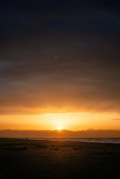 Dramatic Sunset Over Beach with Ocean Waves and Distant Ships