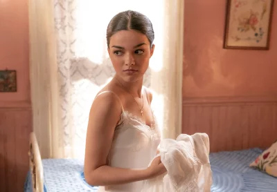 Thoughtful Young Woman in White Lace Slip with Cross Necklace in a Serene Vintage Bedroom image