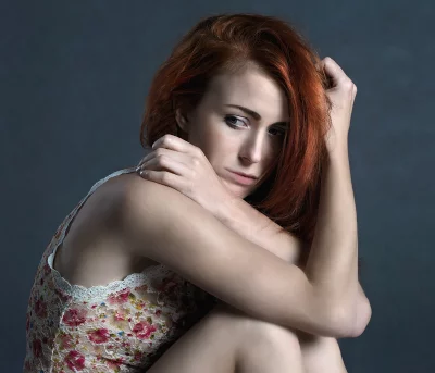 Pensive Redhead Woman in Floral Lace Top with Emotional Gaze on Dark Background image