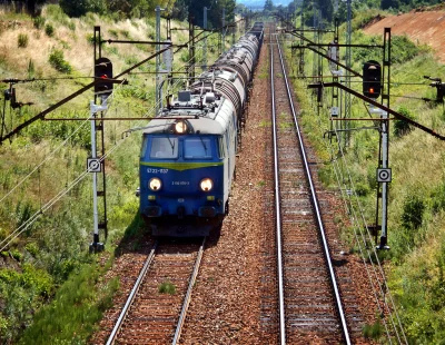 Powerful blue freight train on parallel railway tracks in a vibrant rural landscape image